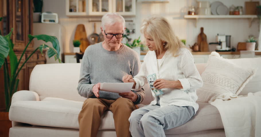 Poor elderly people counting salary and pension benefits, old woman crying. Payment of utility bills, rising costs and inflation, world economy crisis, aged married couple viewing utility bills