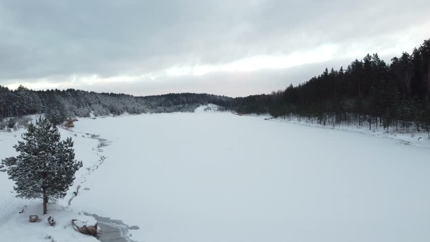 beautiful view from above, snow-covered lake in deep forest. 4k drone.