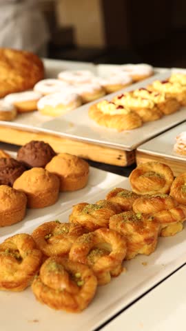 Variety of baked pastries, muffins and sweet rolls displayed on buffet table in cozy bakery or cafe setting for Breakfast, Brunch and Dessert Lovers Savoring Sweet and Savory Treats