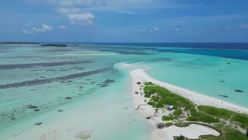 Aerial view of Thulusdhoo island.Maldives.Beautiful white sand beach long sandbar.The white sand beach is surrounded by turquoise water of Indian Ocean.People walking on the beach