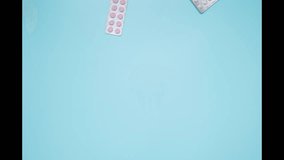 Colorful pill blisters falling on blue surface capturing dynamic motion and health trends. Blisters of pills appear, he brushes away all the pills with his hand. Looping video - Powered by Shutterstock - Get 15% off with code: PIKWIZARD15