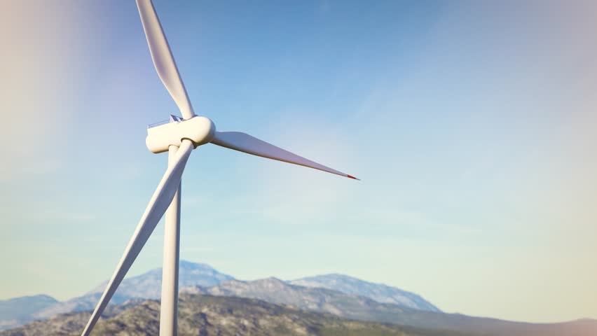 White wind turbine rotating against blue sky and mountain range