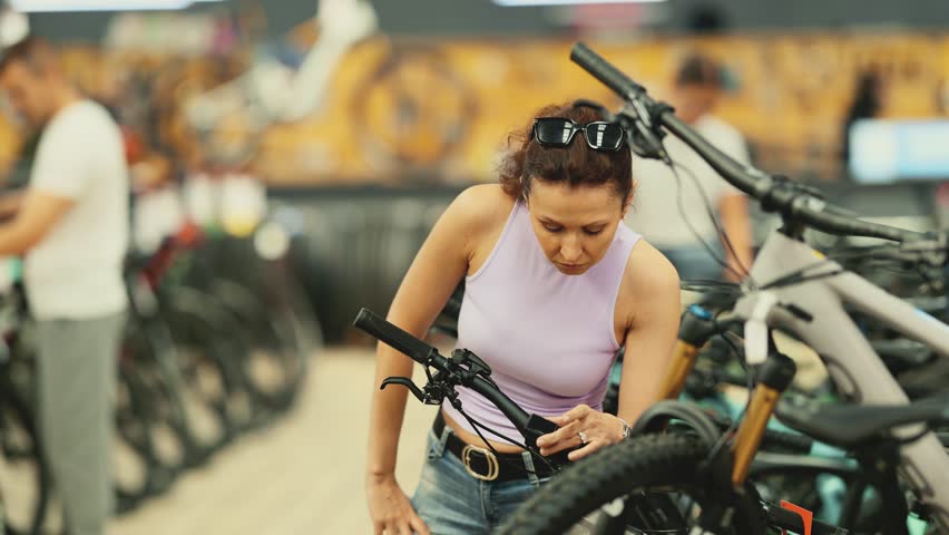 Adult woman buyer chooses bicycle in sports store