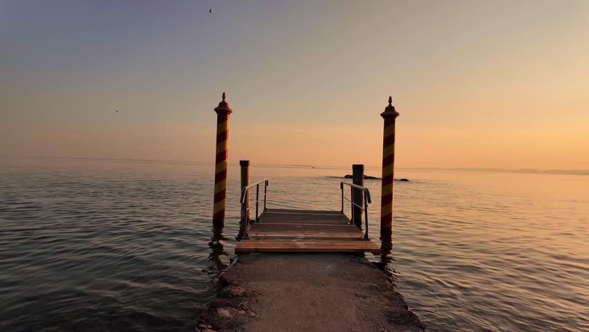 scenic video of wooden pier on the bright golden hour sunset at Italian Garda lake at San Vigilio Point