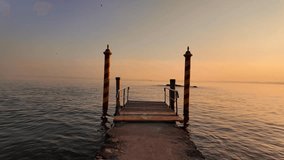scenic video of wooden pier on the bright golden hour sunset at Italian Garda lake at San Vigilio Point - Powered by Shutterstock - Get 15% off with code: PIKWIZARD15