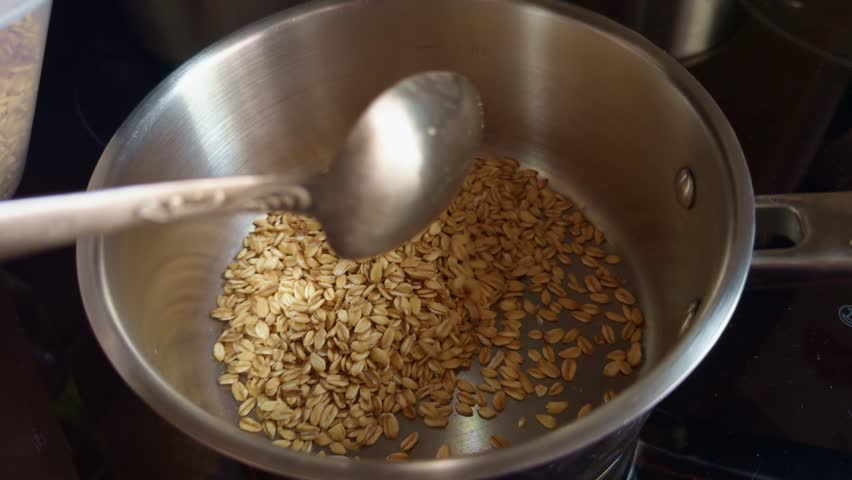 Cooking Oatmeal For Breakfast. Cereal Food On Diet. Homemade Lunch Nutrition On Dieting. Porridge Healthy Food. Preparing Nutritious Breakfast. Raw Oats. Dry Oatmeal Poured Into Pan. Dieting Oatmeal