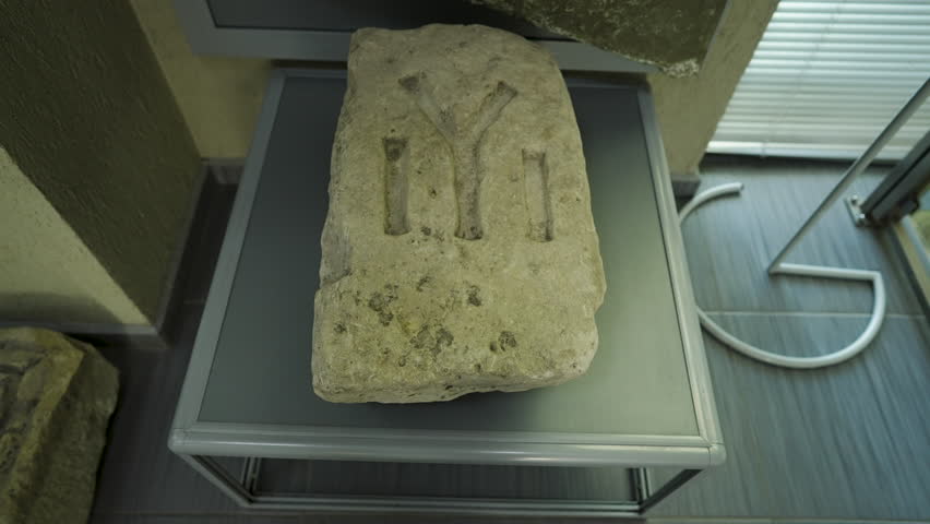 A carved stone artifact bearing symbolic script from ancient Pliska is displayed inside a museum, representing Bulgaria’s early medieval heritage.