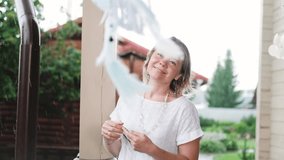 Portrait of a cute young woman in a white dress with a dreamcatcher. The craftswoman made the dreamcatcher herself with white feathers and ribbons. The dreamcatcher sways in the wind. The woman smiles - Powered by Shutterstock - Get 15% off with code: PIKWIZARD15