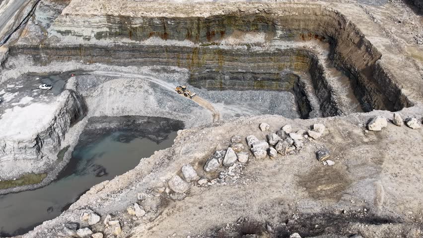 vast open excavation pit with chalky terrain, rubble pathways, and silty runoff channels from high above quarry mine