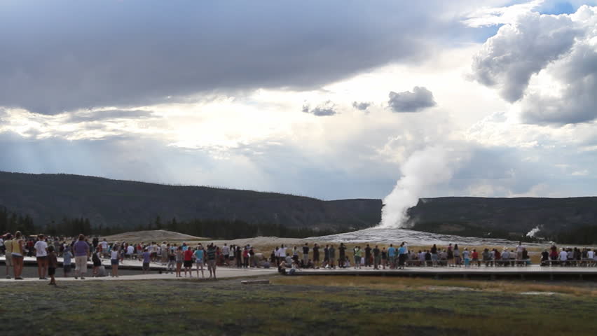 Crowds of people give a sense of scale as they watch Old Faithful geyser