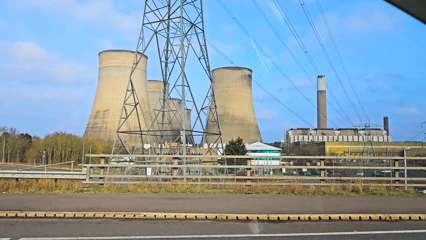 Cooling towers and chimneys standing at large power station. Industrial plant generating electricity with massive concrete structures. Energy facility operating with cooling infrastructure and high