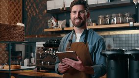 Glad Caucasian barista waiter male man guy bartender worker typing tablet order online app device tech in restaurant catering delivery employee looking at camera small business owner smiling cafeteria - Powered by Shutterstock - Get 15% off with code: PIKWIZARD15