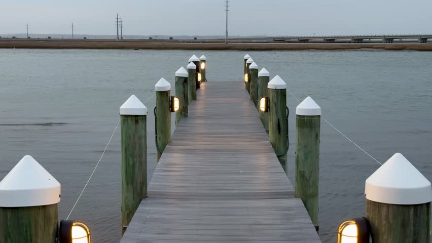 Walking out onto dock with lights over the water in early evening light with grey skies