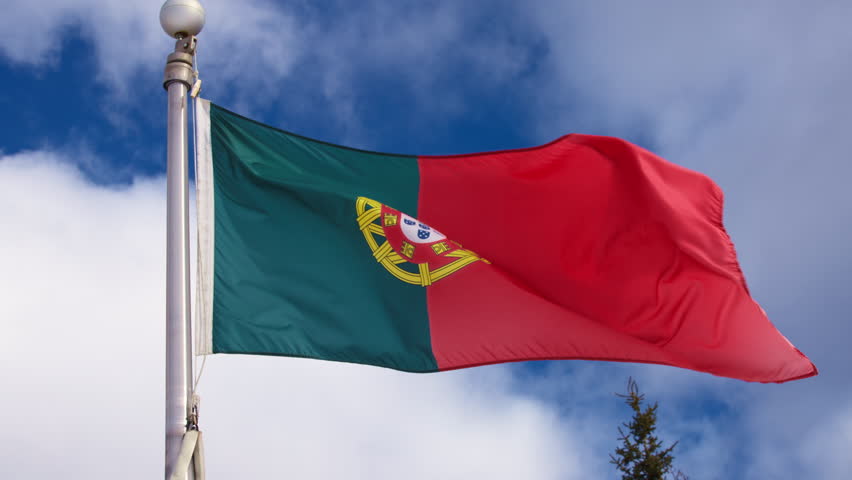Flag of Portugal waving in the wind against blue sky. Slow motion.