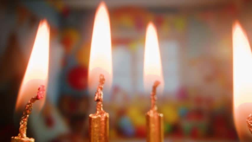 Woman kid child Blowing candles on birthday cake macro, close up of some unlit candles and just one lit candle after blowing out the cake