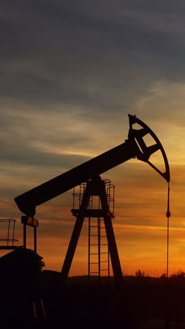 working oil pumps silhouette against sunset. Vertical video