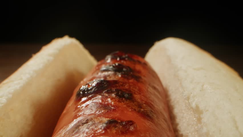 Ketchup tomato sauce Pouring on a Hot Dog with Sausage, close up of cooking hot dog in cafe restaurant.