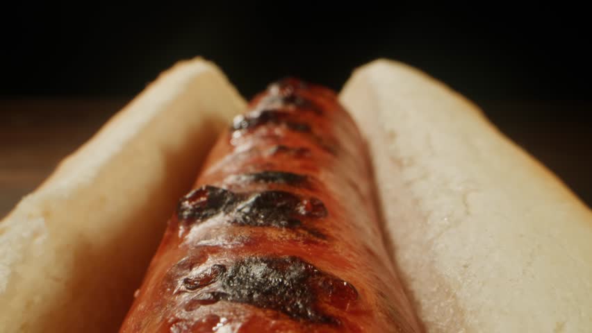 Ketchup tomato sauce Pouring on a Hot Dog with Sausage, close up of cooking hot dog in cafe restaurant.
