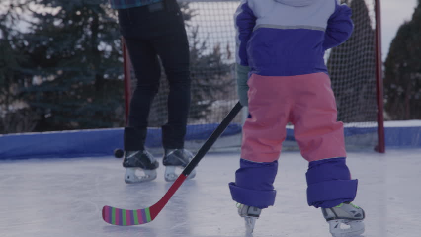 Dad spending time with daughters playing hockey on an outdoor rink