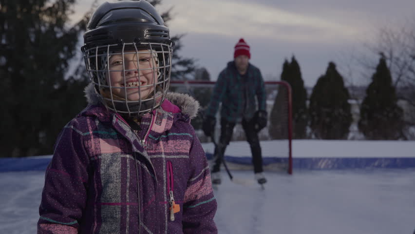 Dad spending time with daughters playing hockey on an outdoor rink