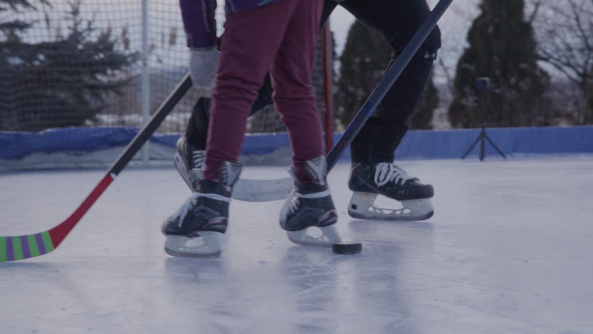 Dad spending time with daughters playing hockey on an outdoor rink