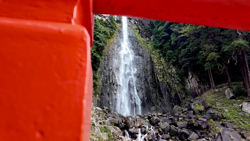 Low angle view of Nachi Falls, framed by a traditional red japanese shrine gate in Nachikatsuura, Japan. Slow Dolly Right