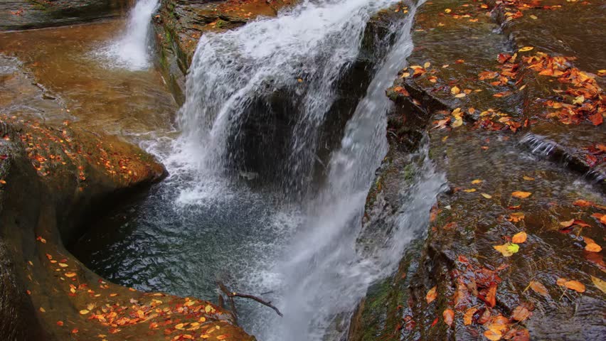 Stunning 4K footage capturing the beauty of a waterfall with golden autumn foliage at Buttermilk Falls State Park in Ithaca, NY.