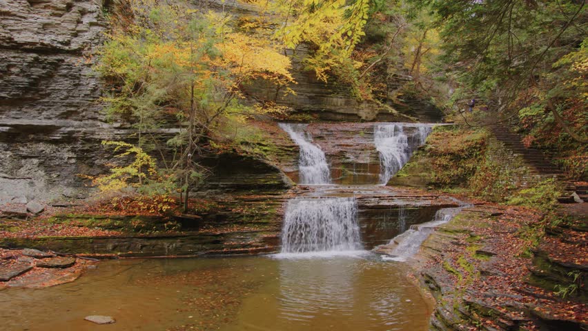 A beautiful 4K shot of vibrant autumn foliage in Buttermilk Falls State Park, Ithaca, NY highlighting golden hues, warm fall colors, and peaceful natural scenery
