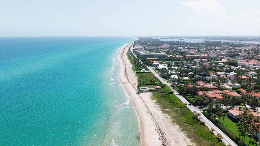Push in drone shot of Municipal Beach and Atlantic Ocean with homes and sand beach during the day in West Palm Beach, Florida, USA