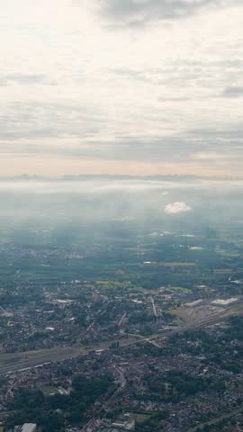 Vertical video. Ghent, Belgium. Sun rays and beautiful clouds. On the ground, a suburb of the city of Ghent with an industrial area and a railway, small houses. Ringvaart in Ghent - water channel, Ae