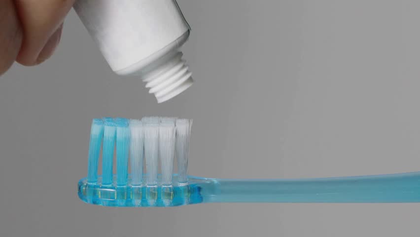 white toothpaste on brush at home. Squeezing toothpaste onto a toothbrush A dental care moment. on a white background, lifestyle oral hygiene routine