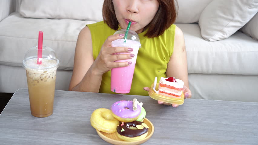 binge eating disorder concept with woman surrounded by donuts, cakes, sweet drinks like milk tea and coffee, sugar addiction and the impact of a high-sugar, unhealthy eating lifestyle 