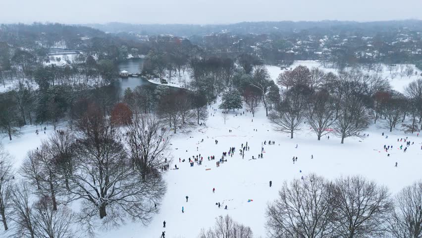 Aerial static shot of people sledding down a hill in Piedmont Park Atlanta, Georgia on January 10th 2025.