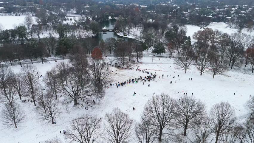 Aerial rotating shot of people sledding in Piedmont park Atlanta, Georgia on January 10th 2025.