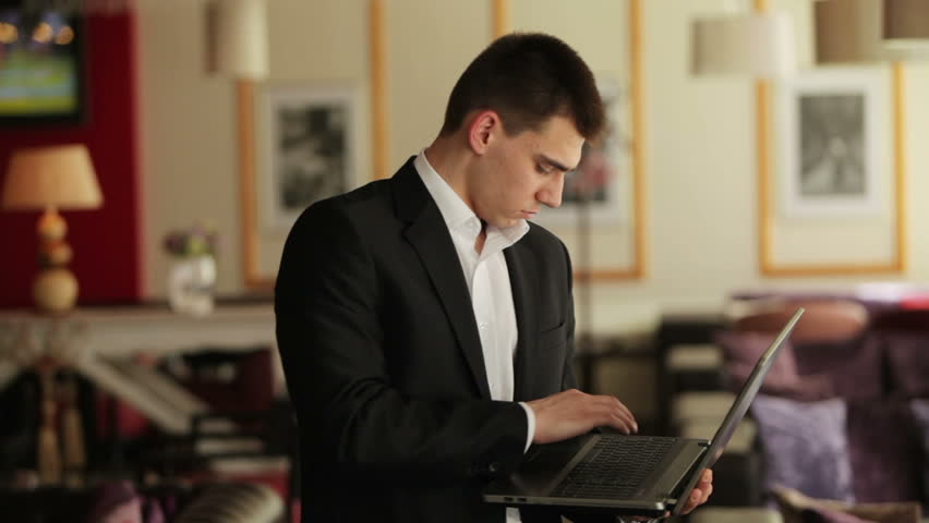 Businessman standing in a cafe with a laptop