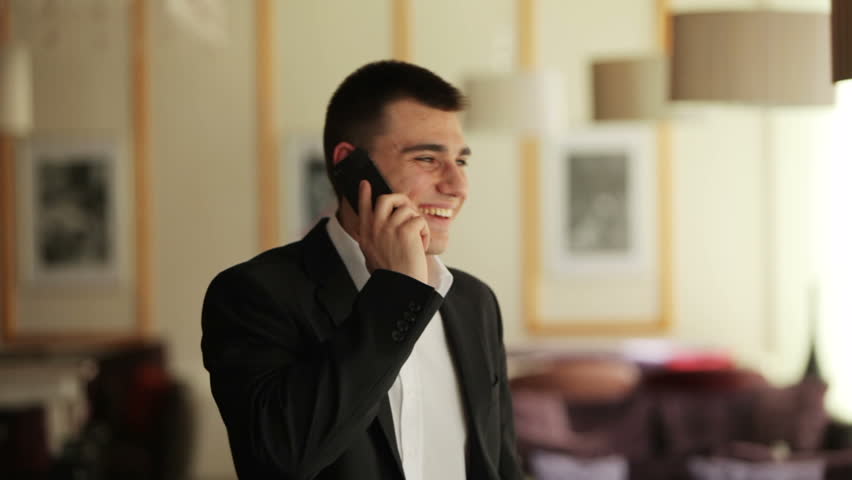 Businessman talking on the phone, laughing and looking at camera