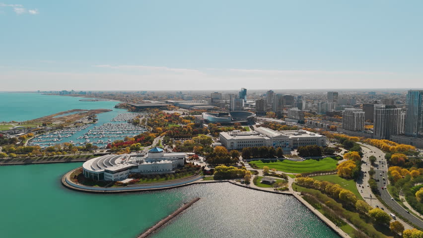 Wide drone shot of Chicago skyline in autumn, showcasing modern skyscrapers and fall light.