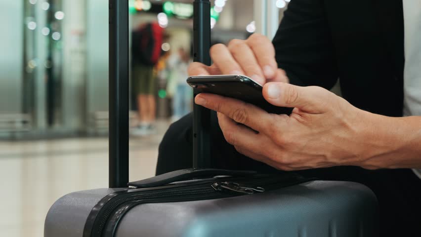 Businessman Uses Laptop, Waiting for a Flight in Airport Terminal or train station, Traveling Entrepreneur Working Online On Computer Sitting in a Boarding Lounge of Airline Hub with Airplanes
