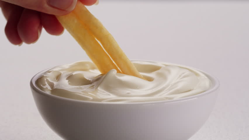 Curry cheese lemon sauce close up, fast food cafe Pouring fries potato and fry chicken in mayo yellow creamy cheese sauce close-up. Eat chicken nuggets with Peruvian sauce. Fast and junk food concept.