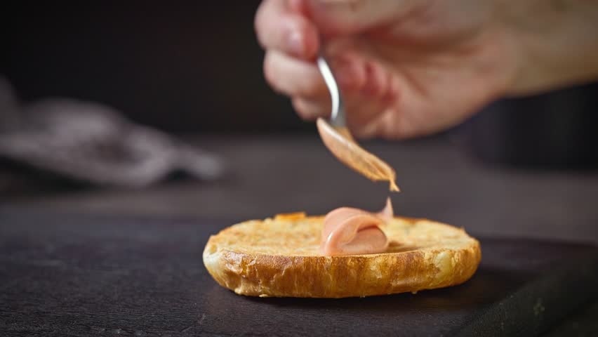 cook put burger bread bun on black wooden cutting board and put sauce on bread bun, food closeup