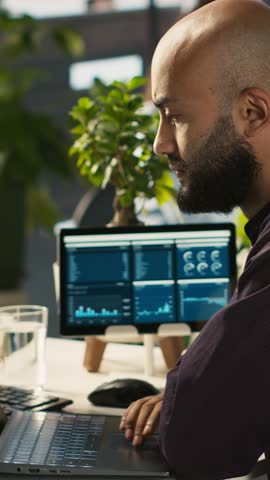 Vertical video Employee in office celebrating achievement while looking at laptop screen, expressing excitement over successful results. Man happy about positive business accomplishment, camera A
