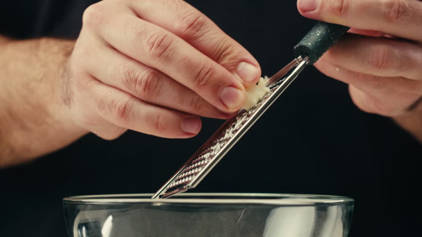 Garlic with grater, Close up of hand grating garlic with a small metal grater, cleaning and cooking on kitchen. 