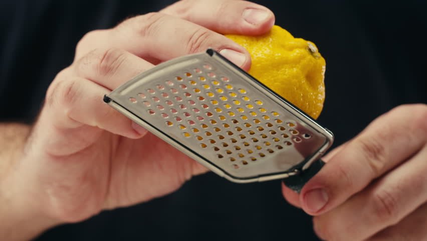 Lemon And Grater, Macro Close Up Shot of a Professional Chef Grating Lemon Zest for lemonade salad.