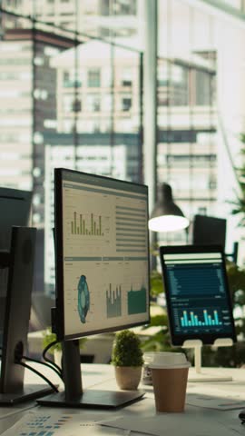 Vertical video Tablet and PC on desk displaying financial graphs of company profits performance metrics. Data analytics on device display showing corporate business earnings KPIs. panning shot