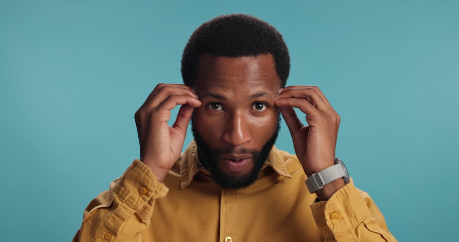 Explosion, news and face of black man in studio for surprise, announcement and notification. Promotion, wow and shocked with person on blue background for results, alert and mind blown emoji