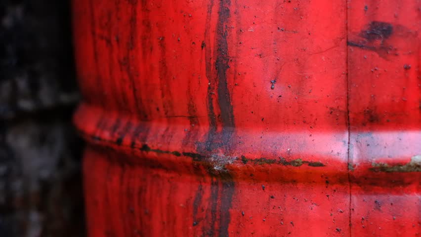 A red barrel with a rusted surface. The barrel is old and has a worn appearance. The rusted surface gives the barrel a sense of age and history