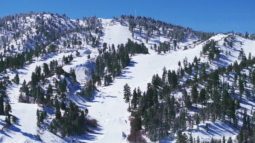Experience skiing and snowboarding at Big Bear, California, amidst breathtaking views of snow and mountains in a captivating winter wonderland