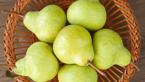 Green pears slowly rotating inside woven wicker basket, resting on rustic wooden surface, showcasing fresh agricultural produce with natural organic aesthetic. - Powered by Shutterstock - Get 15% off with code: PIKWIZARD15