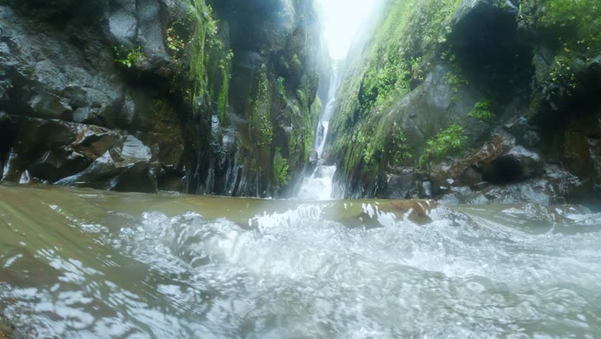 4K low angle close up shot of running water of stream comes form Satsada waterfall in Maharashtra, India. Waterfall flowing between two mountain creek during monsoon. 