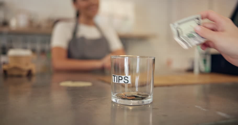 Hand, person and money for tips at cafe of customer gratitude, community contribution and payment method. Closeup, client and jar for cash transaction, good service and staff reward of finance income